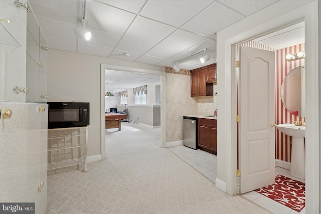 corridor featuring track lighting, baseboards, a paneled ceiling, light tile patterned floors, and light colored carpet