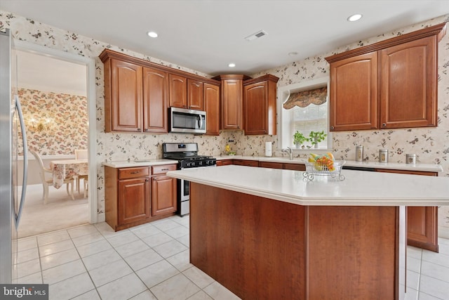 kitchen featuring stainless steel appliances, wallpapered walls, light countertops, light tile patterned floors, and a sink