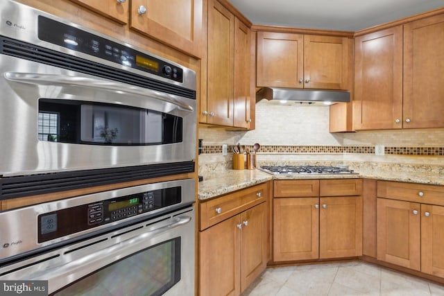 10611 Tattersall Dr, Manassas, VA 20112 - kitchen with appliances with stainless steel finishes, under cabinet range hood, light stone countertops, and tasteful backsplash