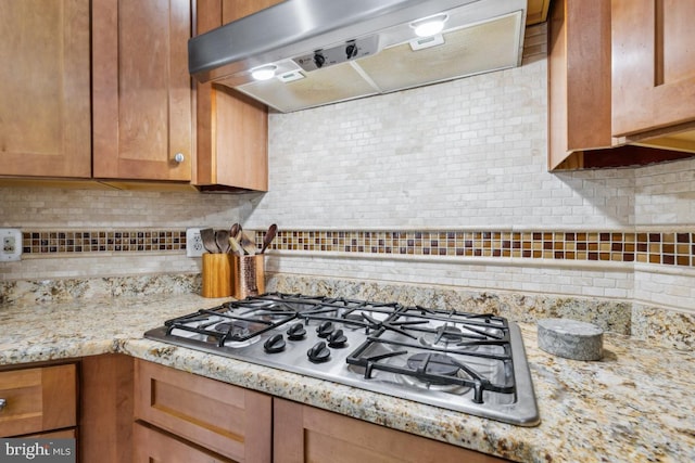 10611 Tattersall Dr, Manassas, VA 20112 - kitchen with stainless steel gas cooktop, extractor fan, tasteful backsplash, light stone countertops, and brown cabinets