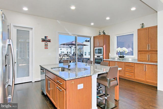 23109 Cottonwillow Sq, Brambleton, VA 20148 - kitchen with a sink, dark wood-type flooring, appliances with stainless steel finishes, a center island with sink, and a breakfast bar