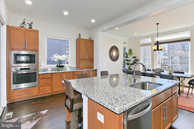 23109 Cottonwillow Sq, Brambleton, VA 20148 - kitchen featuring appliances with stainless steel finishes, a sink, dark wood finished floors, brown cabinetry, and crown molding