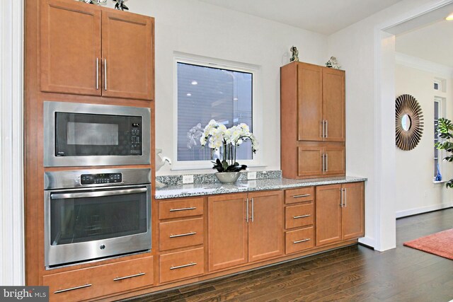 23109 Cottonwillow Sq, Brambleton, VA 20148 - kitchen featuring stainless steel oven, built in microwave, dark wood-style floors, light stone counters, and brown cabinetry