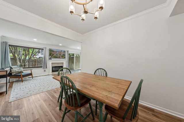 10707 Muirfield Dr, Potomac, MD 20854 - dining area with wood finished floors, a chandelier, crown molding, baseboards, and a glass covered fireplace