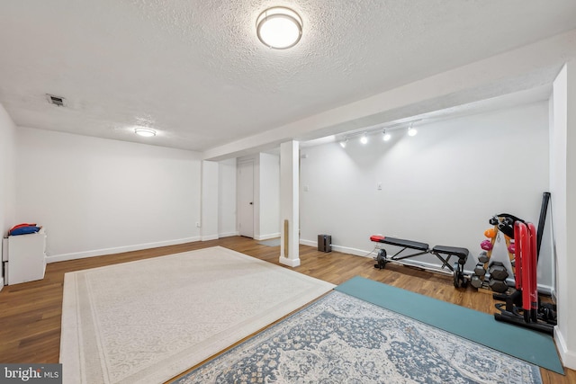 10707 Muirfield Dr, Potomac, MD 20854 - workout area featuring a textured ceiling, wood finished floors, baseboards, and track lighting