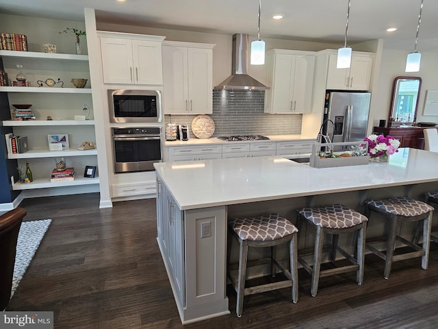 kitchen featuring stainless steel appliances, wall chimney range hood, white cabinets, dark wood-type flooring, and recessed lighting