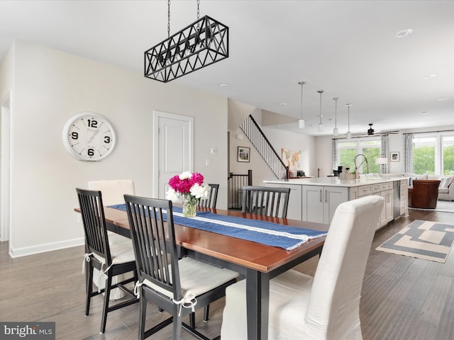 dining room with dark wood-type flooring, ceiling fan, stairs, and baseboards