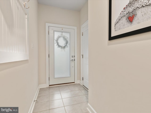 doorway featuring light tile patterned floors and baseboards