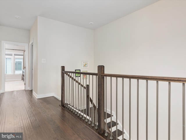 corridor with wood finished floors, an upstairs landing, and baseboards