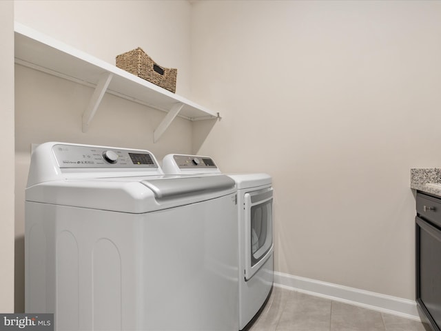 laundry room featuring washing machine and dryer, baseboards, and light tile patterned floors