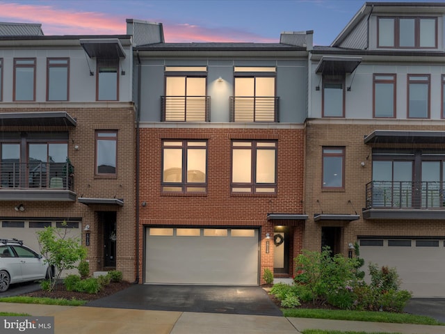multi unit property featuring a garage, driveway, and brick siding