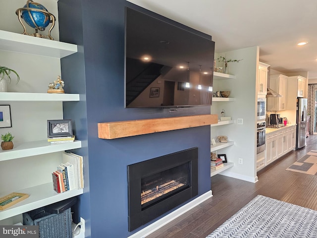living area featuring dark wood-type flooring, a glass covered fireplace, and recessed lighting