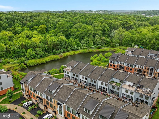 aerial view of residential area featuring a nearby body of water and a forest