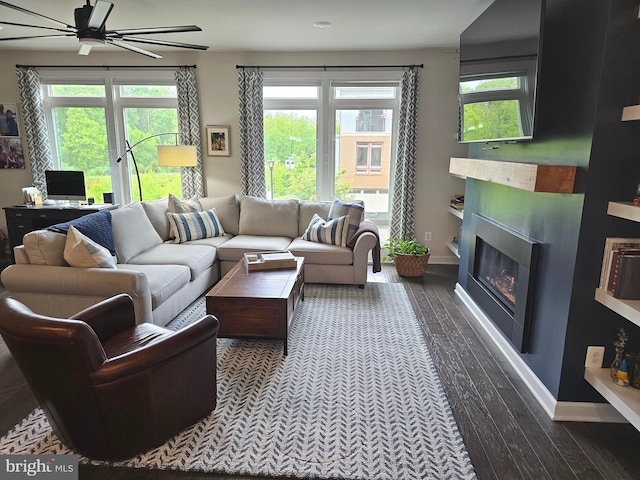 living area with a ceiling fan, a fireplace, dark wood-style floors, and healthy amount of natural light