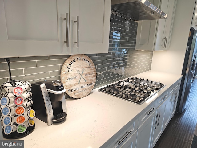 kitchen with extractor fan, appliances with stainless steel finishes, light countertops, and backsplash