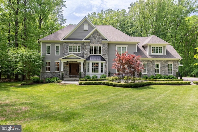craftsman inspired home with stone siding, a front yard, and a shingled roof