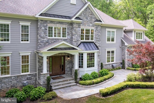 craftsman house with a standing seam roof, stone siding, and a shingled roof