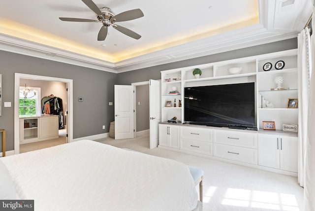 bedroom featuring a tray ceiling, ornamental molding, light colored carpet, and a ceiling fan