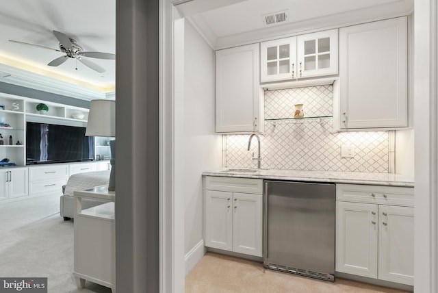indoor wet bar with refrigerator, a ceiling fan, decorative backsplash, light carpet, and crown molding