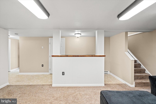 finished basement featuring light carpet, stairway, baseboards, and a baseboard radiator