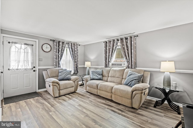 living room with healthy amount of natural light, light wood finished floors, cooling unit, and baseboards