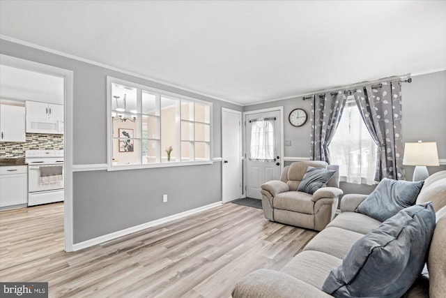 living room featuring crown molding, light wood-style floors, baseboards, and a chandelier