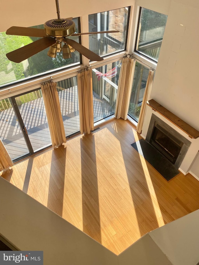 411 Lynetree Dr Unit 12-C, West Chester, PA 19380 - unfurnished living room featuring wood finished floors, healthy amount of natural light, ceiling fan, a towering ceiling, and a fireplace with flush hearth