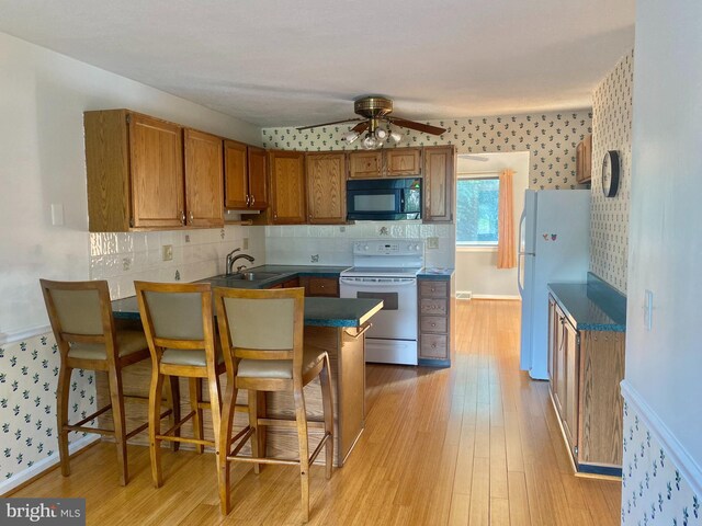 411 Lynetree Dr Unit 12-C, West Chester, PA 19380 - kitchen with white appliances, a peninsula, brown cabinets, a ceiling fan, and wallpapered walls