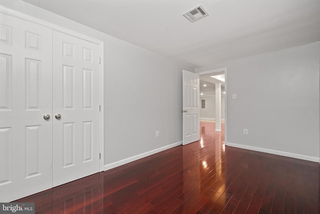 unfurnished bedroom with hardwood / wood-style flooring, baseboards, and a closet