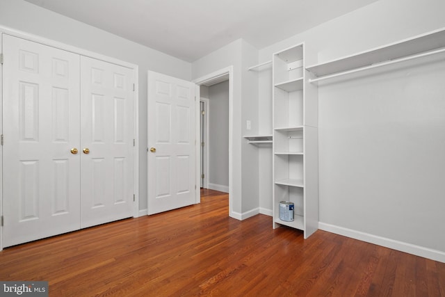 unfurnished bedroom with baseboards, wood finished floors, and a closet