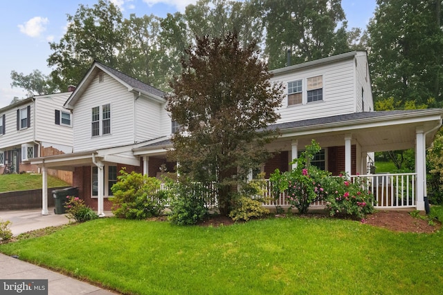 view of front of property featuring covered porch, a front yard, and brick siding