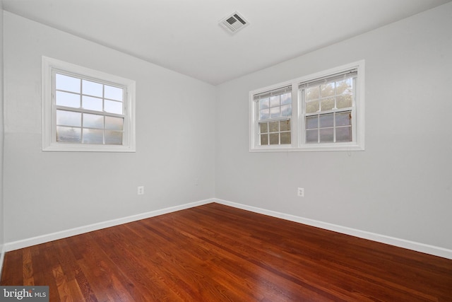 unfurnished room featuring baseboards and dark wood-style flooring