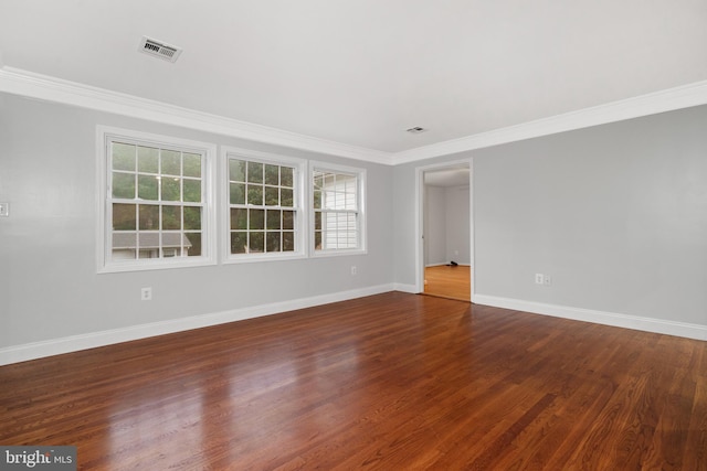 empty room with dark wood-type flooring, baseboards, and ornamental molding