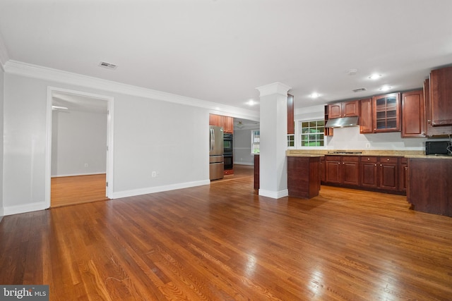 kitchen with under cabinet range hood, dark wood finished floors, open floor plan, crown molding, and glass insert cabinets