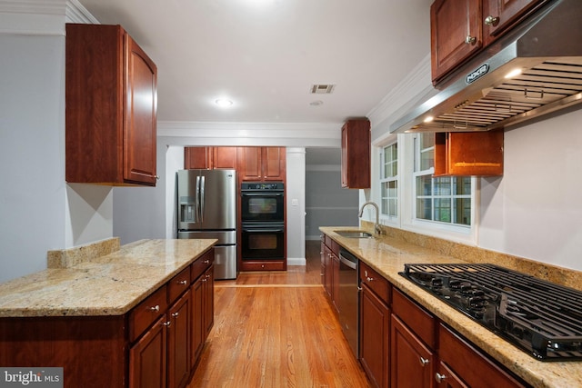 kitchen featuring under cabinet range hood, black appliances, a sink, light wood-style floors, and light stone counters