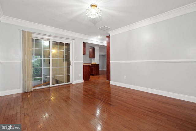 spare room with wood-type flooring, baseboards, ornamental molding, and a chandelier