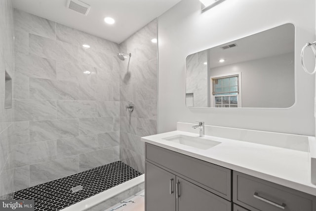 bathroom with vanity, tiled shower, and recessed lighting