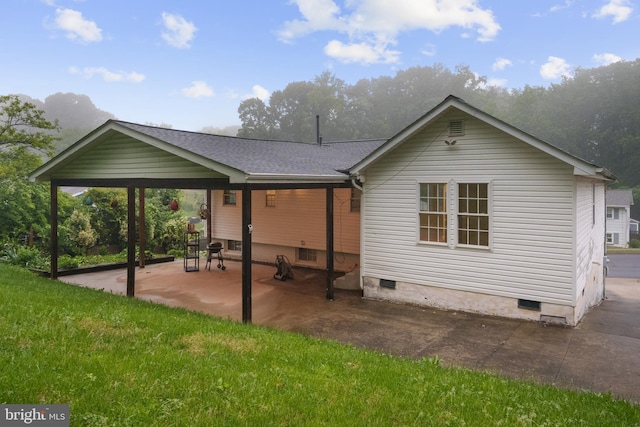 back of house featuring crawl space, a patio, a shingled roof, and a lawn