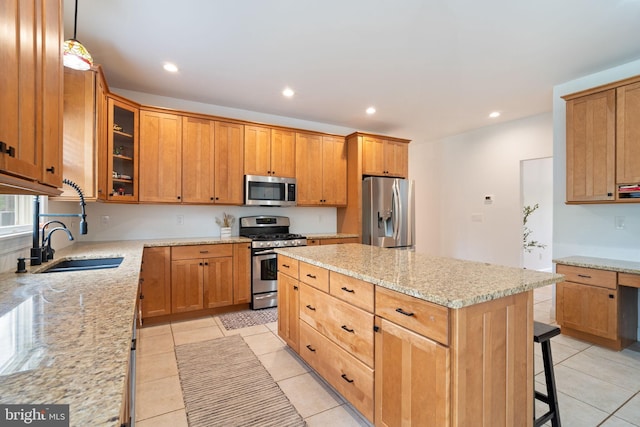 kitchen with stainless steel appliances, a center island, light stone counters, a kitchen breakfast bar, and light tile patterned floors