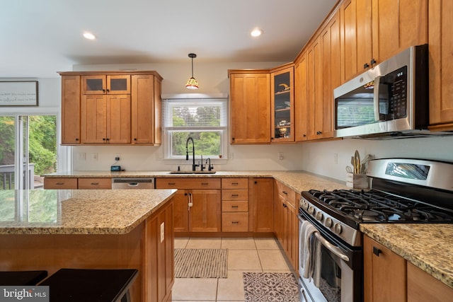 kitchen with appliances with stainless steel finishes, a sink, light stone counters, decorative light fixtures, and recessed lighting