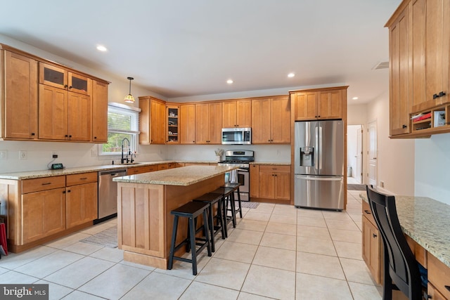 kitchen with appliances with stainless steel finishes, a sink, recessed lighting, a kitchen breakfast bar, and a kitchen island