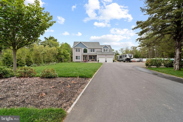 view of front of house with an attached garage, a front yard, and asphalt driveway