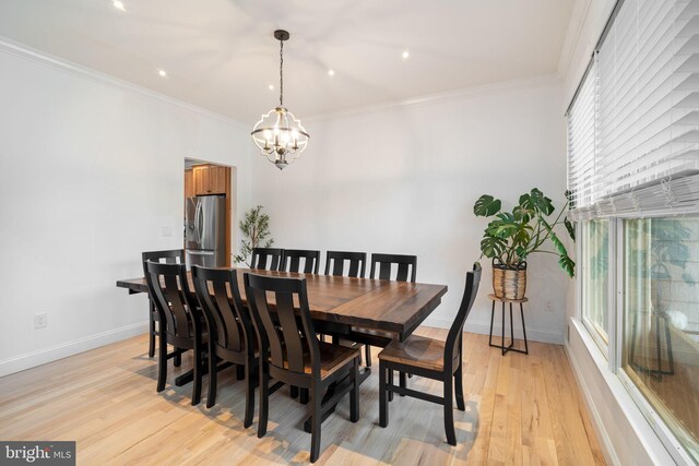 dining space featuring a chandelier, light wood-type flooring, baseboards, and ornamental molding