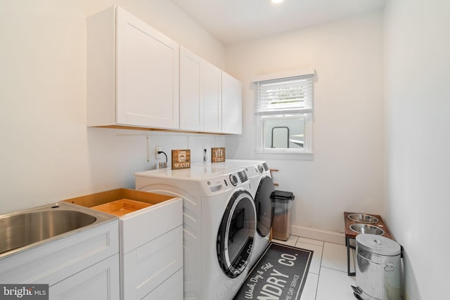 washroom with cabinet space, washing machine and dryer, tile patterned flooring, and baseboards