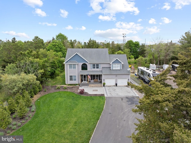 view of front of house featuring driveway, a front lawn, a garage, and covered porch