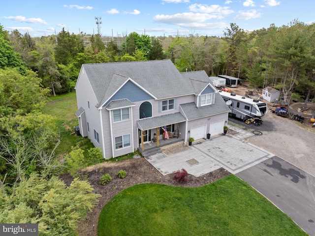 view of front of property featuring a porch, asphalt driveway, a garage, a shingled roof, and a front yard