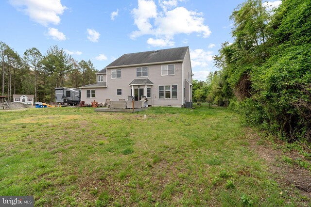 back of property with a wooden deck, a lawn, and cooling unit