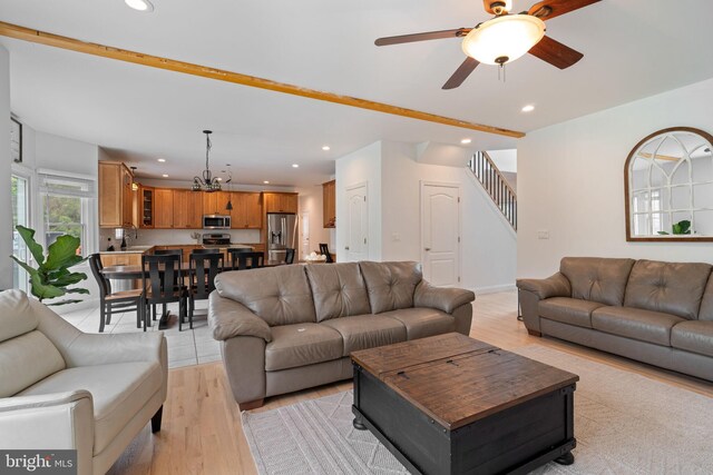 living room featuring recessed lighting, stairs, light wood-style floors, a ceiling fan, and a chandelier