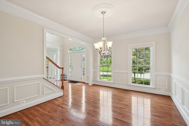 711 Bleak Hill Pl, Upper Marlboro, MD 20774 - unfurnished dining area with a chandelier, stairway, a decorative wall, wood finished floors, and ornamental molding