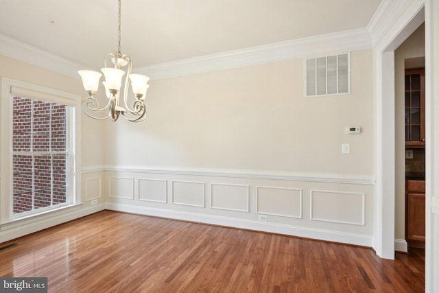 711 Bleak Hill Pl, Upper Marlboro, MD 20774 - unfurnished dining area featuring a chandelier, ornamental molding, wainscoting, wood finished floors, and a decorative wall